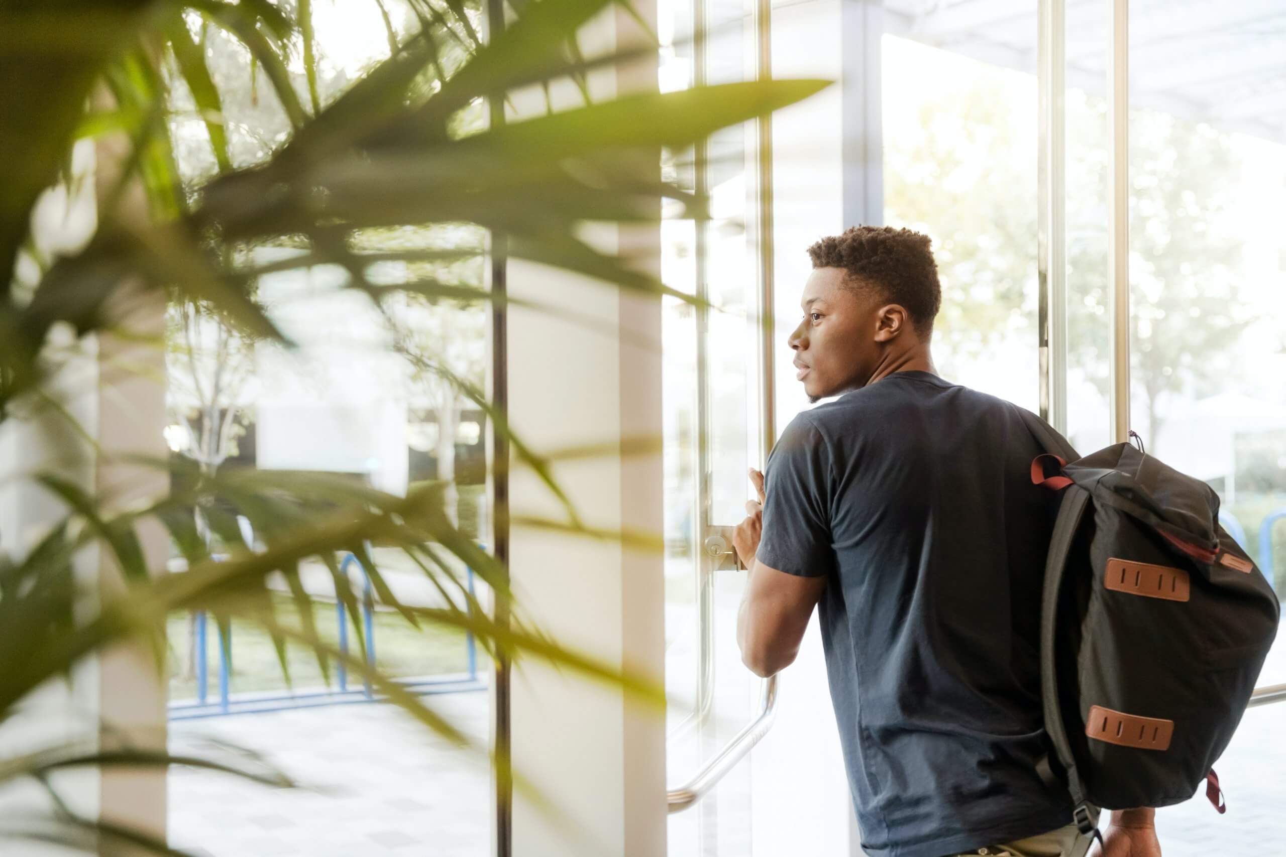 man leaving building wearing backpack